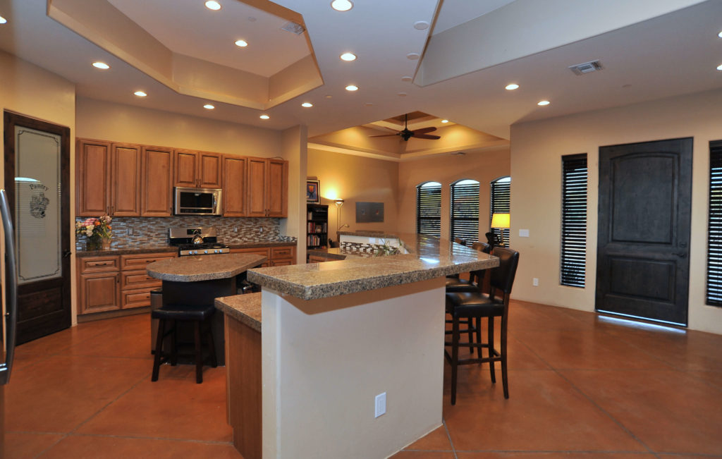 Image of large kitchen with island. Brown cabinets and brown, large-tile flooring.